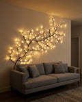 Willow vine light spanning the width of a sofa on a living room wall with the lights on