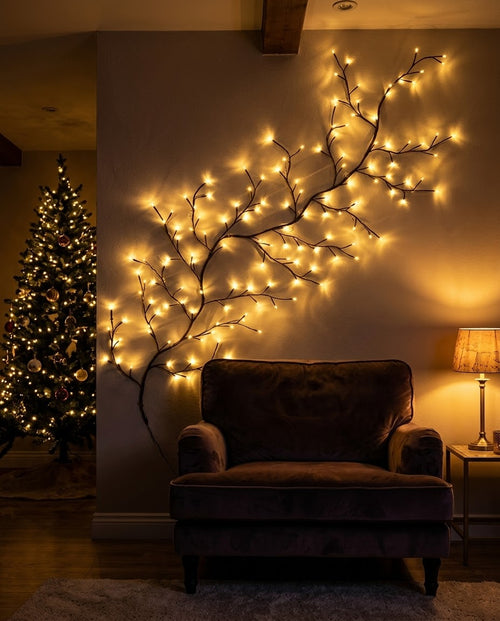 Willow vine light with warm LEDs on the wall above a velvet armchair beside a lit Christmas tree