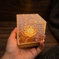 Givre crystal lamp glowing amber on a dark stone surface